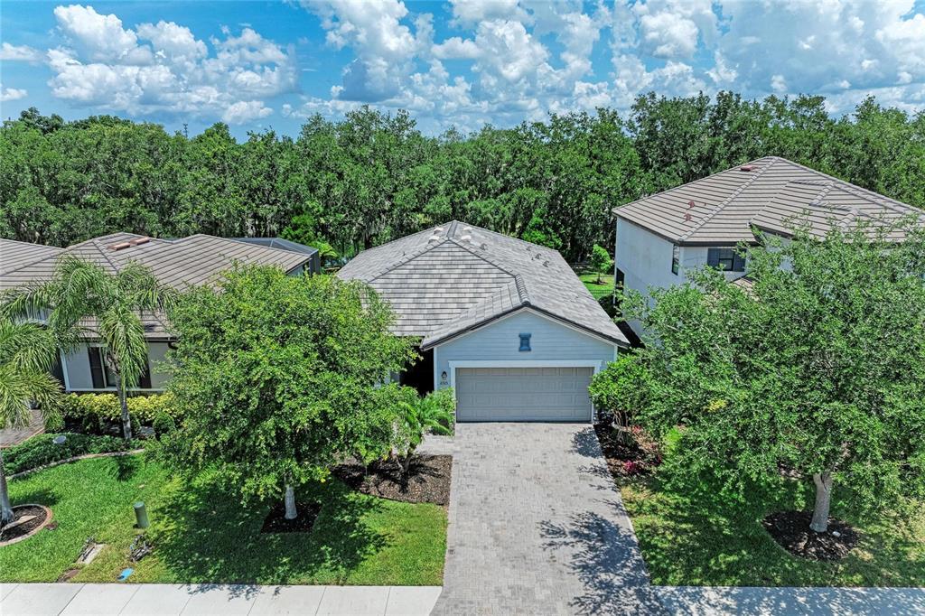 An aerial view of a single-story house with a gray tiled roof and paved driveway — 11515 SWEETGRASS DRIVE, BRADENTON, FL