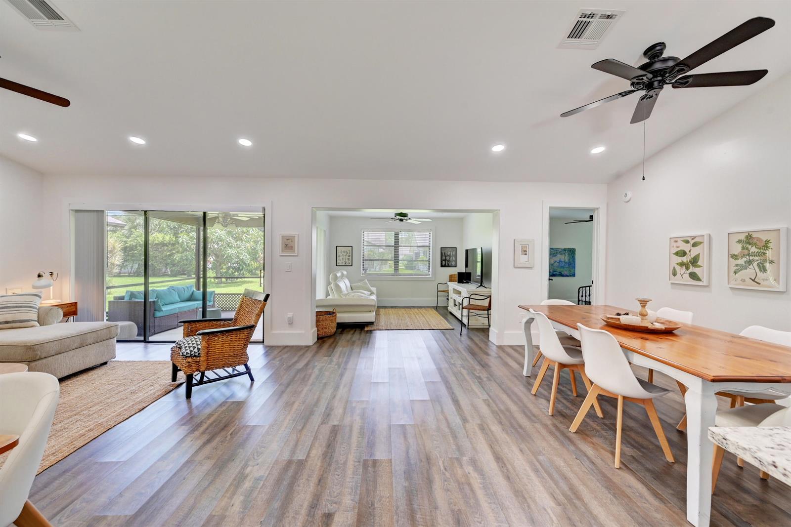An open-concept living and dining area features wood-look flooring, white walls, and a sliding door — 2756 Carnation Court, Delray Beach FL 33445, DELRAY BEACH, FL