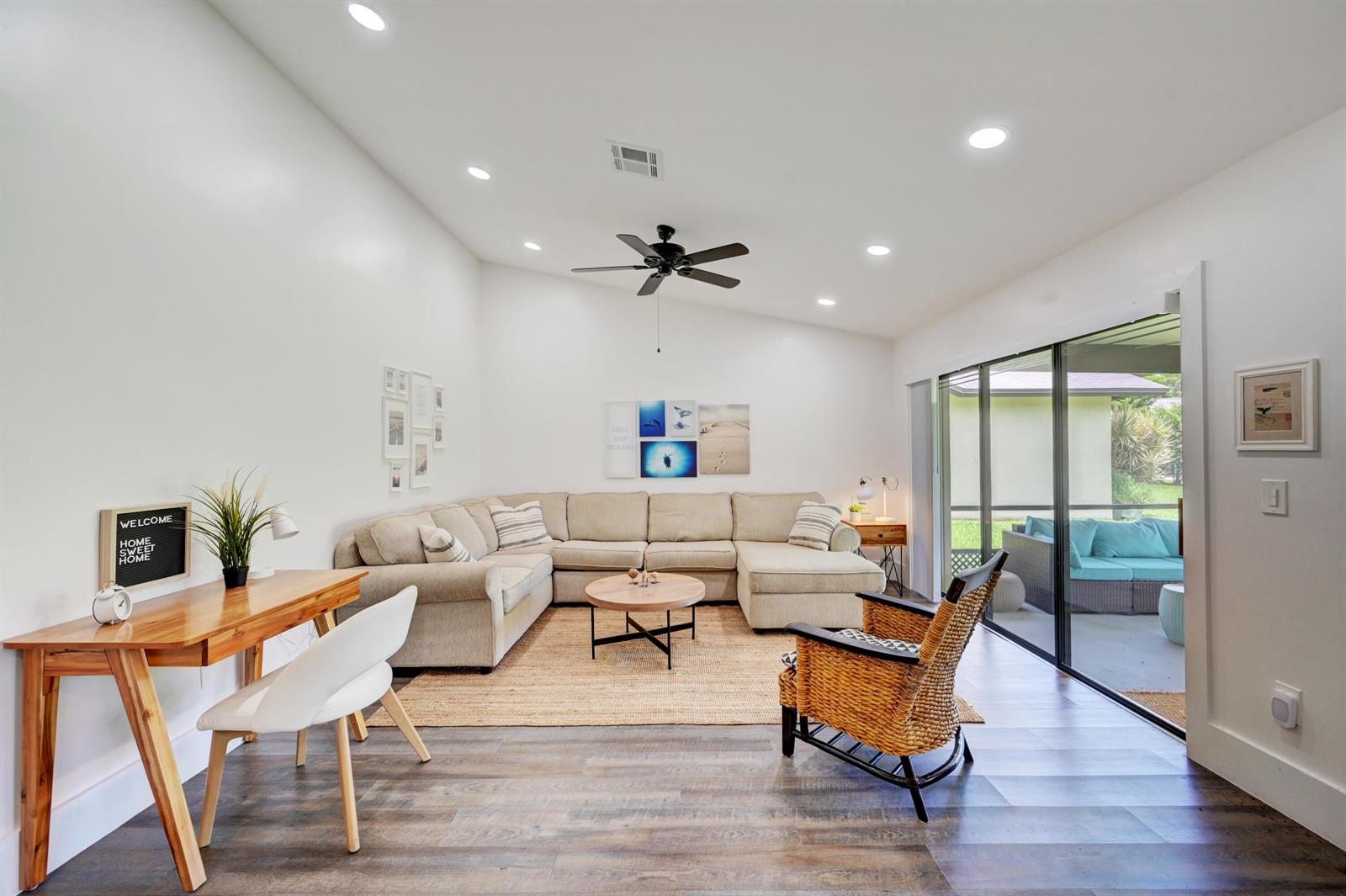 A living room features a sectional sofa, a wooden desk, and a sliding glass door — 2756 Carnation Court, Delray Beach FL 33445, DELRAY BEACH, FL