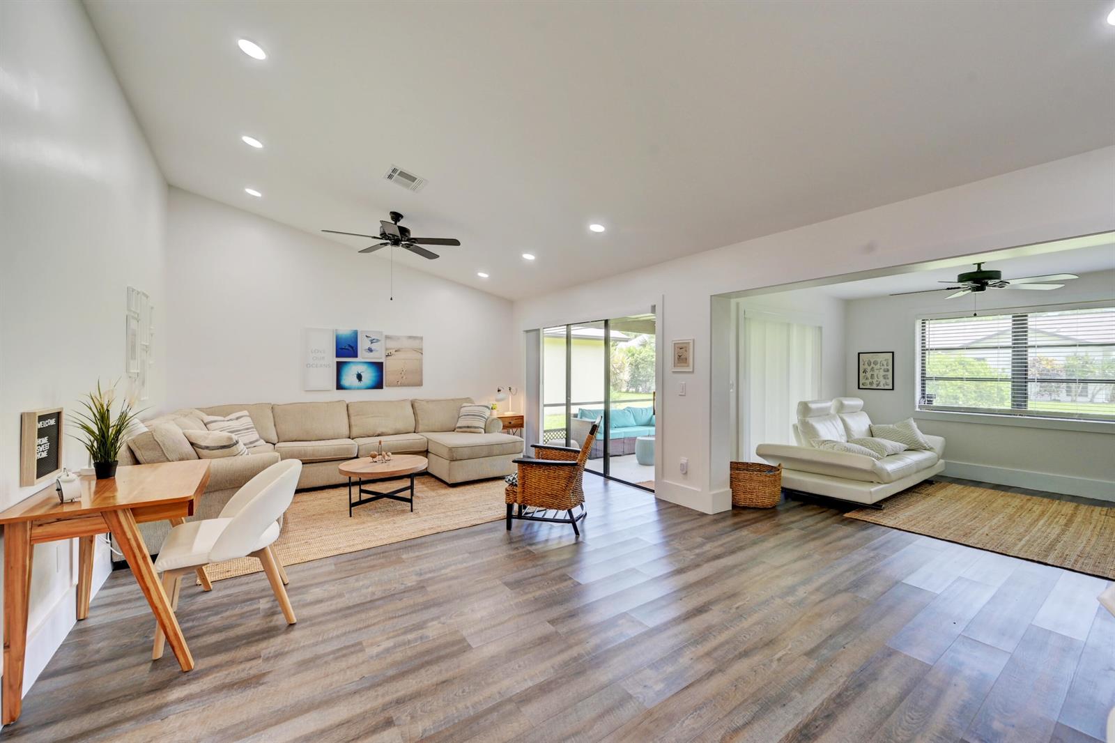 A spacious living area features wood-look flooring, a large sectional sofa, and a separate seating area — 2756 Carnation Court, Delray Beach FL 33445, DELRAY BEACH, FL