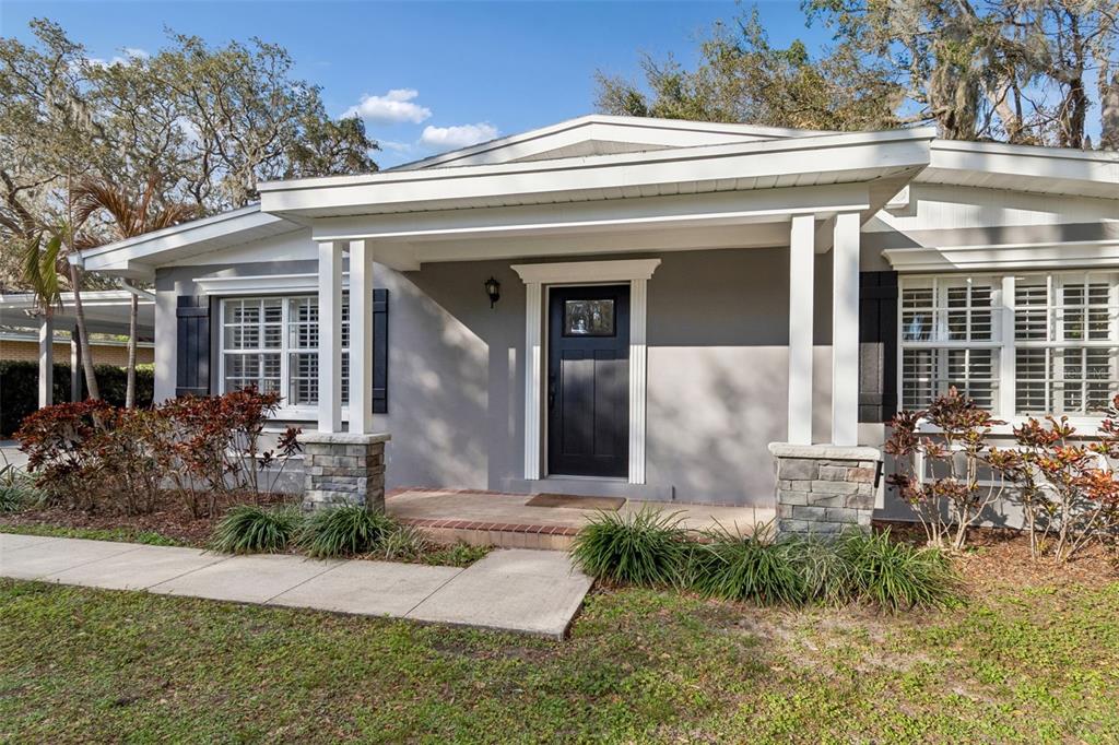 A gray house with a covered porch, stone-based columns, and a black front door — 308 BRENTWOOD DRIVE, TEMPLE TERRACE, FL