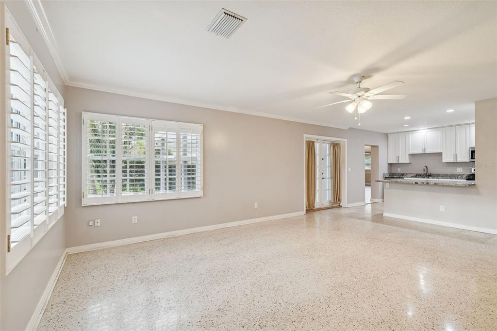 A spacious living room features light-colored walls, white plantation shutters, and speckled terrazzo flooring — 308 BRENTWOOD DRIVE, TEMPLE TERRACE, FL