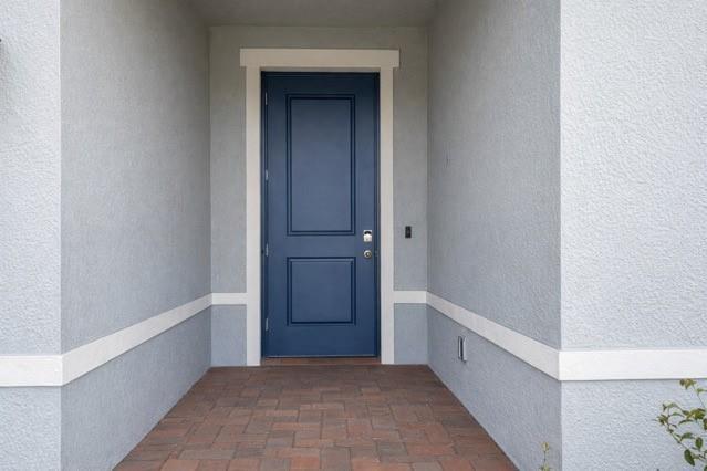 A blue front door is centered in a covered entryway with light gray stucco walls — 6740 Rumine Circle, Vero Beach FL 32967, VERO BEACH, FL