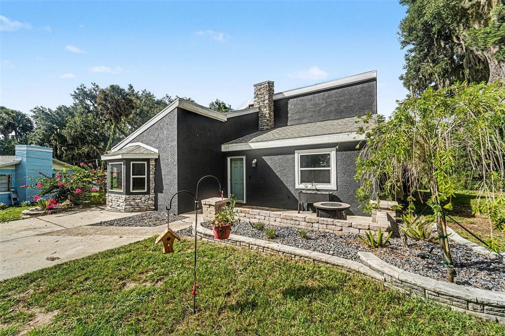 A dark gray house with a stone chimney and a front patio with stone walls — 7238 HILLCREST STREET, LEESBURG, FL