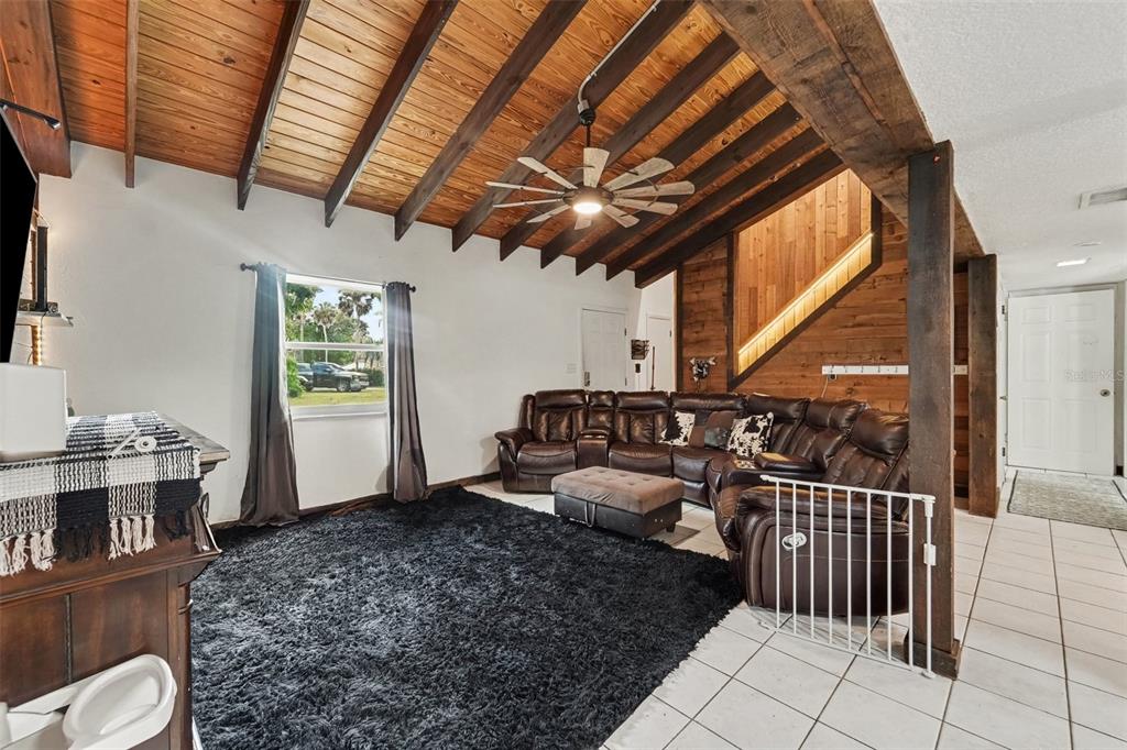 A living room features a vaulted wood-paneled ceiling, a large sectional sofa, and tile flooring — 7238 HILLCREST STREET, LEESBURG, FL