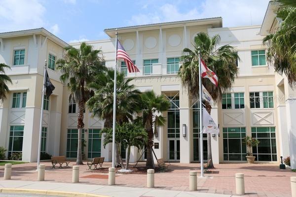 The exterior of a multi-story city hall building features palm trees and three flagpoles — WYOLA AVENUE, NORTH PORT, FL