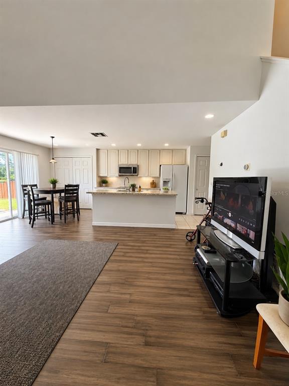 An open-concept living area features a kitchen with white cabinets, an island, and wood flooring — 13347 BRIAR FOREST COURT, ORLANDO, FL