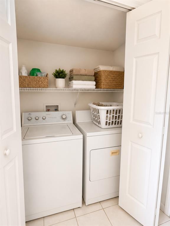 A laundry closet contains a white top-loading washer and dryer with a wire storage shelf — 13347 BRIAR FOREST COURT, ORLANDO, FL