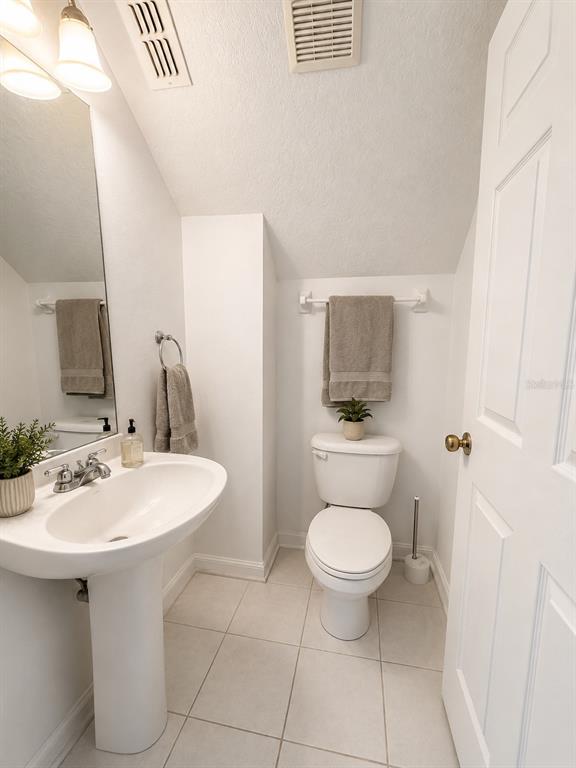 A small bathroom features a white pedestal sink, a toilet, and light-colored floor tiles — 13347 BRIAR FOREST COURT, ORLANDO, FL