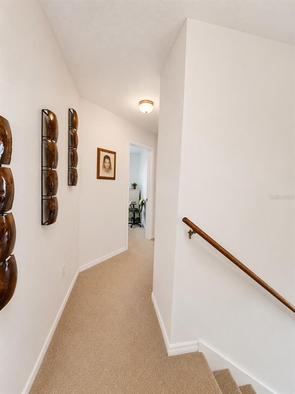 A carpeted hallway leads to a room with a wooden handrail along the stairs — 13347 BRIAR FOREST COURT, ORLANDO, FL