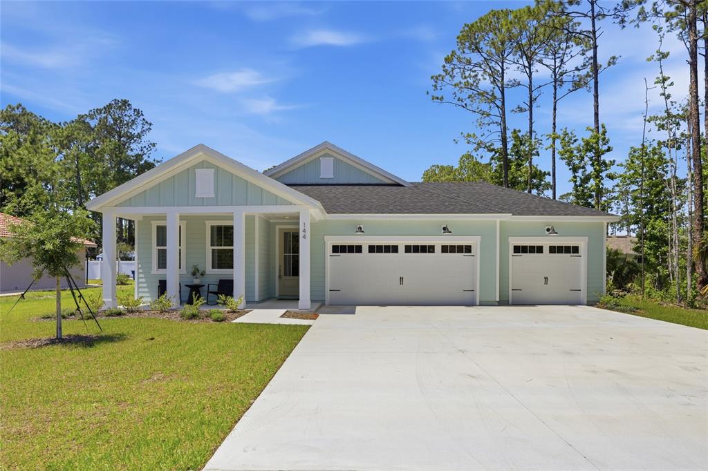 A light green single-story house with a three-car garage and a covered front porch — 144 POINT PLEASANT DRIVE, PALM COAST, FL