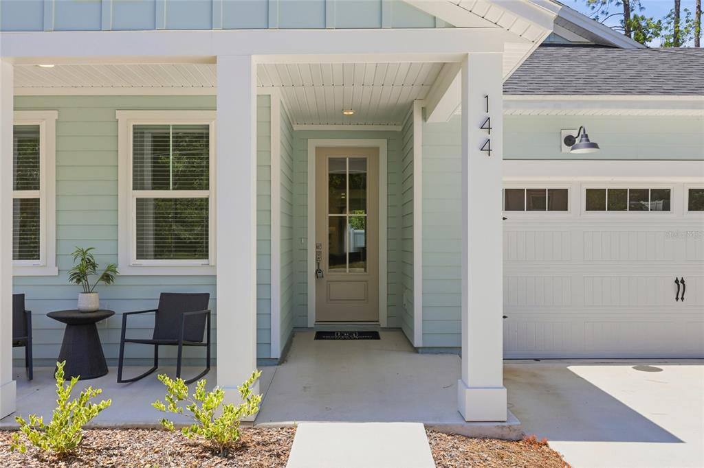 The exterior of a house features light blue siding, a covered porch, and a garage — 144 POINT PLEASANT DRIVE, PALM COAST, FL