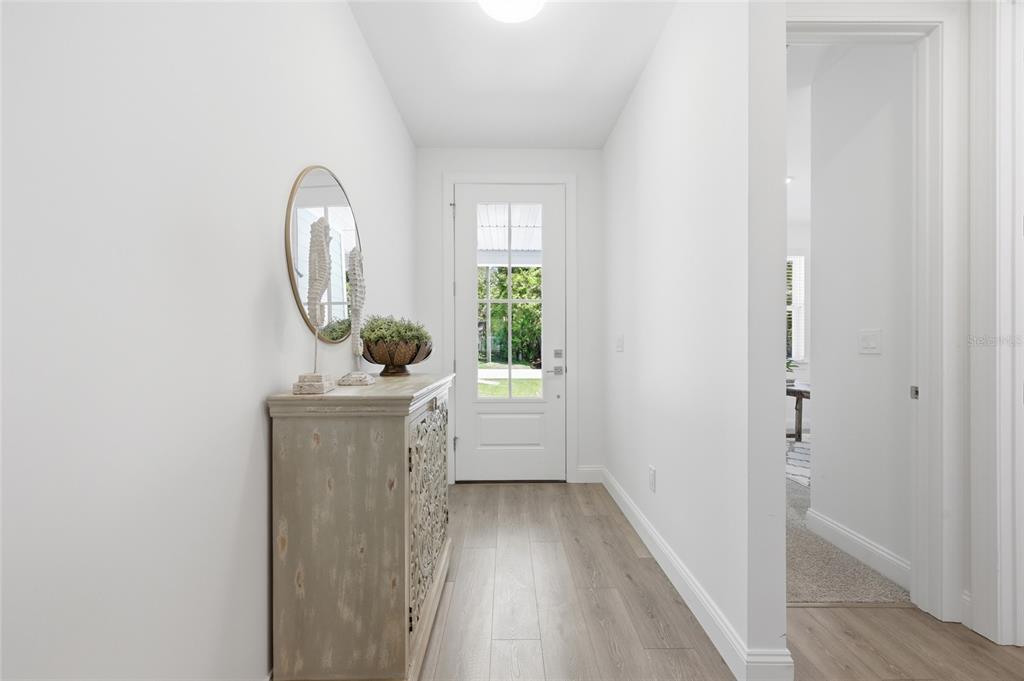A bright entryway features light wood-look flooring, a white front door, and a decorative cabinet — 144 POINT PLEASANT DRIVE, PALM COAST, FL