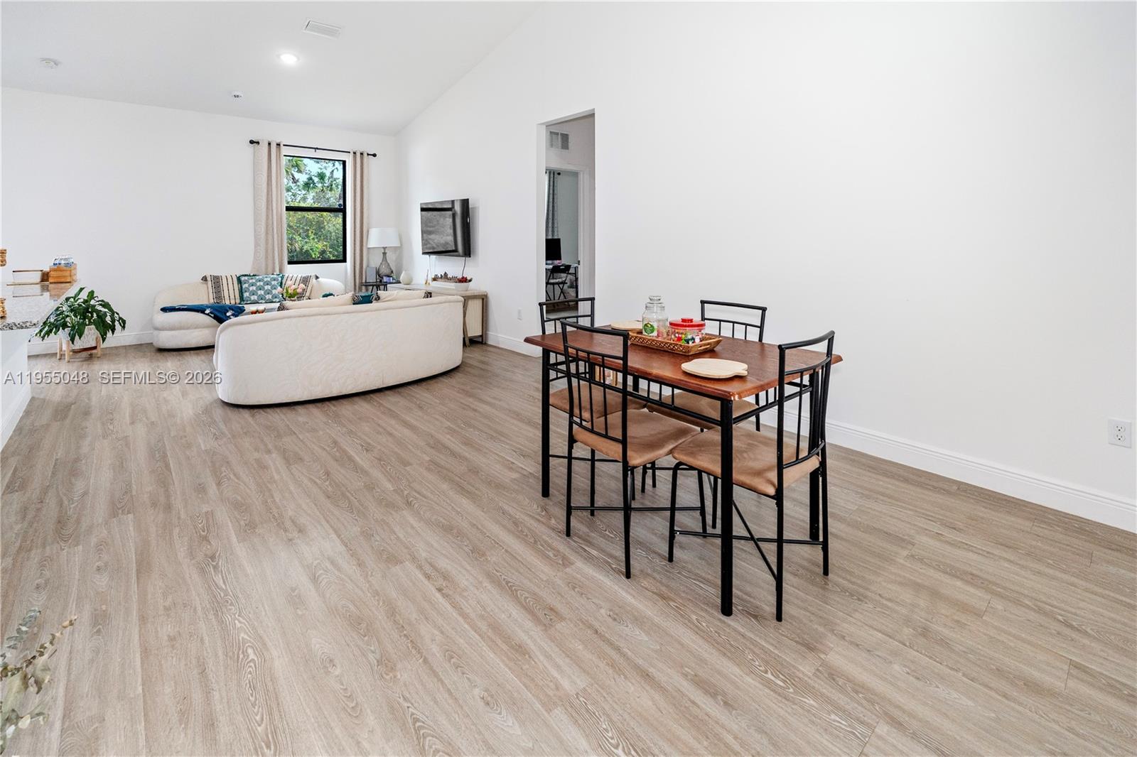 A dining area with a wooden table and chairs sits in an open-concept living space — 8031 Sandy Cir, La Belle FL 33935, LA BELLE, FL