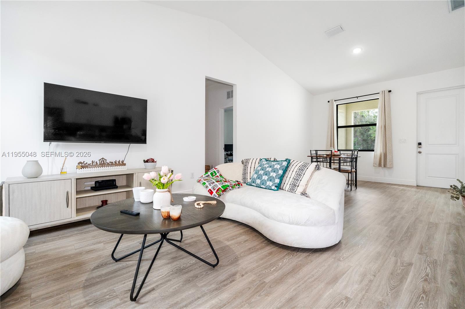 A living room features a curved white sofa, a round coffee table, and wood-look flooring — 8031 Sandy Cir, La Belle FL 33935, LA BELLE, FL