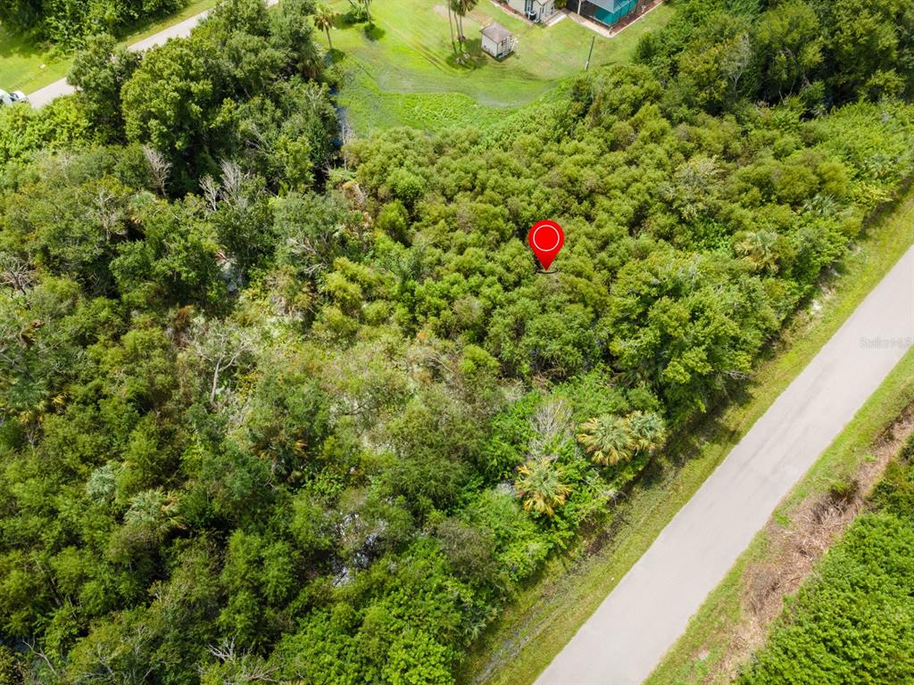 An aerial view shows a wooded, undeveloped lot with a red location marker — 22447 MOROCCO AVENUE, PORT CHARLOTTE, FL