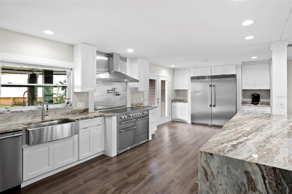 A modern kitchen features white cabinets, stainless steel appliances, and a large marble-topped island — 10525 HOMESTEAD DRIVE, TAMPA, FL
