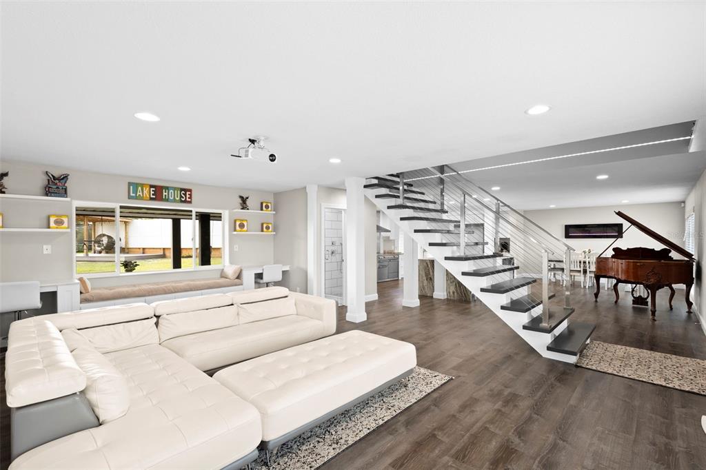 A modern living room features a white sectional sofa, a floating staircase, and a grand piano — 10525 HOMESTEAD DRIVE, TAMPA, FL
