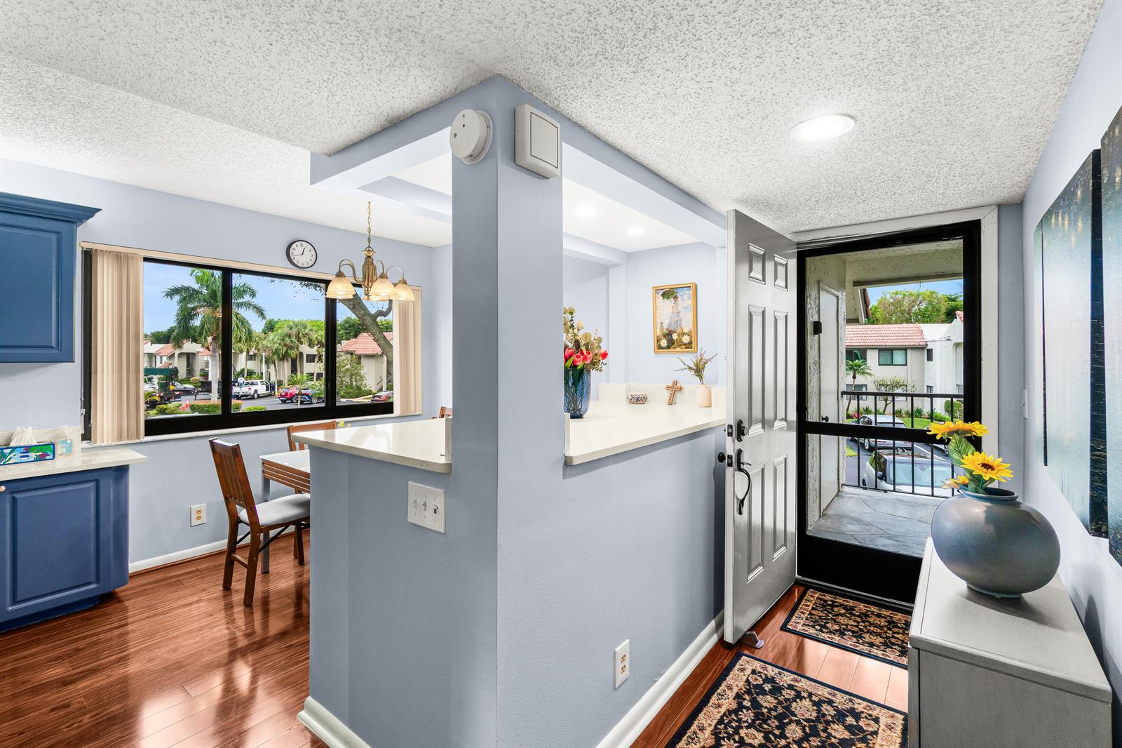 A dining area with blue cabinets and a breakfast bar opens to an entryway door — 5687 Fairway Park Drive, Boynton Beach FL 33437, BOYNTON BEACH, FL