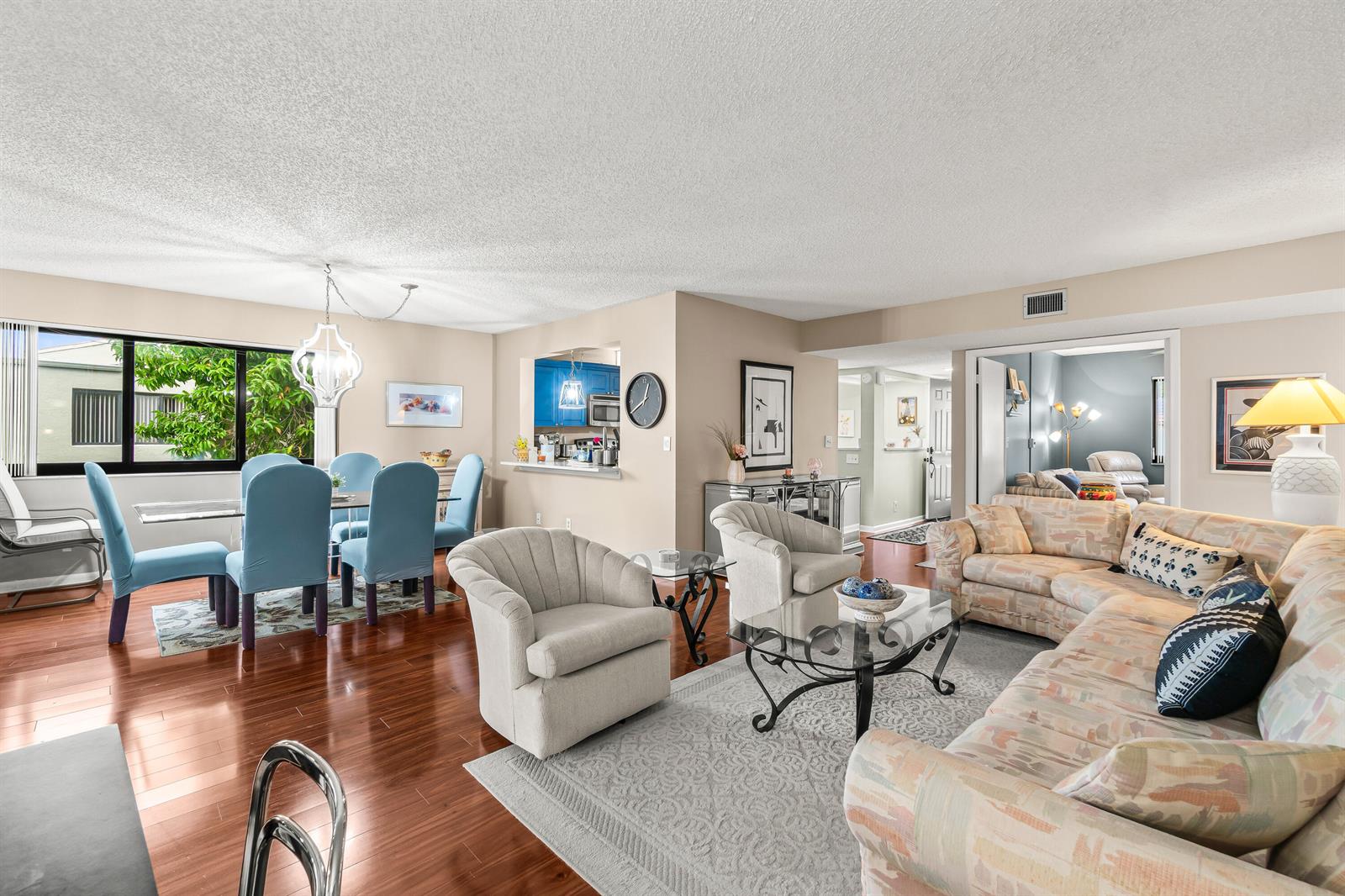 An open-concept living and dining area features hardwood floors, light-colored furniture, and a kitchen pass-through — 5687 Fairway Park Drive, Boynton Beach FL 33437, BOYNTON BEACH, FL