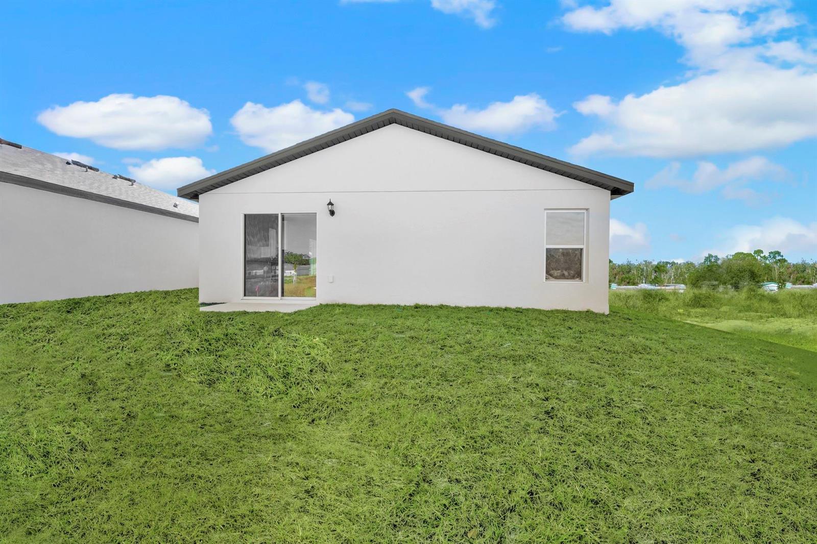 The exterior of a white, single-story house features a sliding glass door and one window — 8556 105th Avenue, Vero Beach FL 32967, VERO BEACH, FL