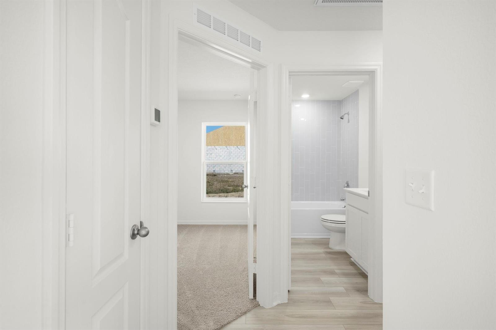 A hallway leads to a carpeted bedroom and a bathroom with light-colored wood-look flooring — 8556 105th Avenue, Vero Beach FL 32967, VERO BEACH, FL