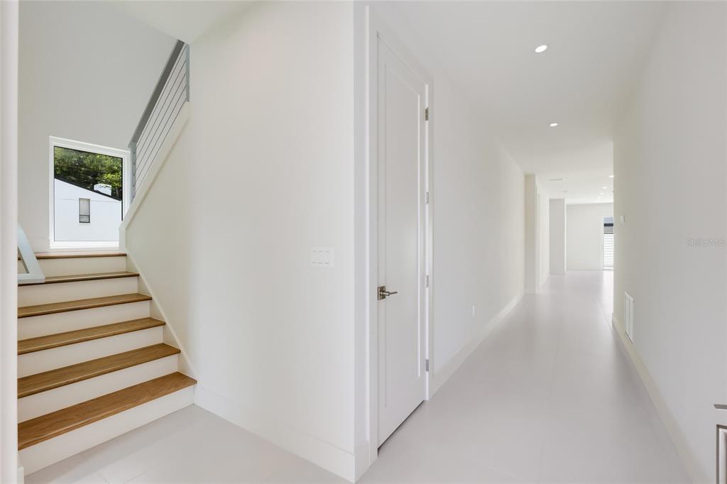 A bright hallway features a wooden staircase with a metal railing and a white door — 2596 FLOYD STREET, SARASOTA, FL