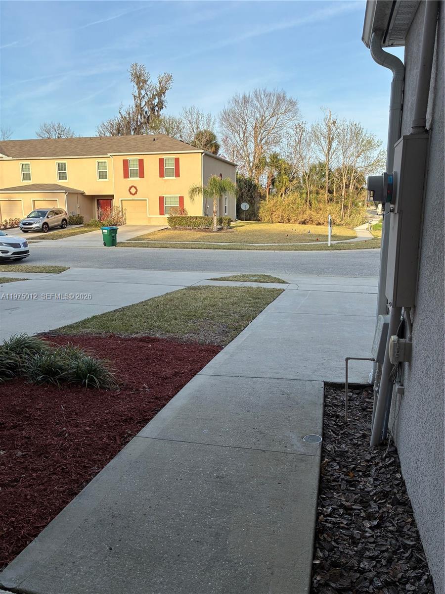 A view from a concrete walkway looking toward a tan two-story residential building — 1612 Primo Ct, Daytona FL 32117, DAYTONA, FL