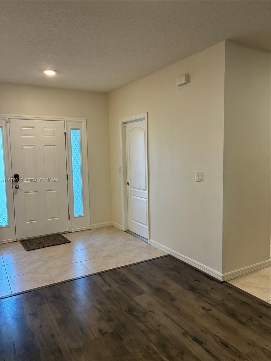 An entryway features a white front door, a side door, tile flooring, and wood-look flooring — 1612 Primo Ct, Daytona FL 32117, DAYTONA, FL