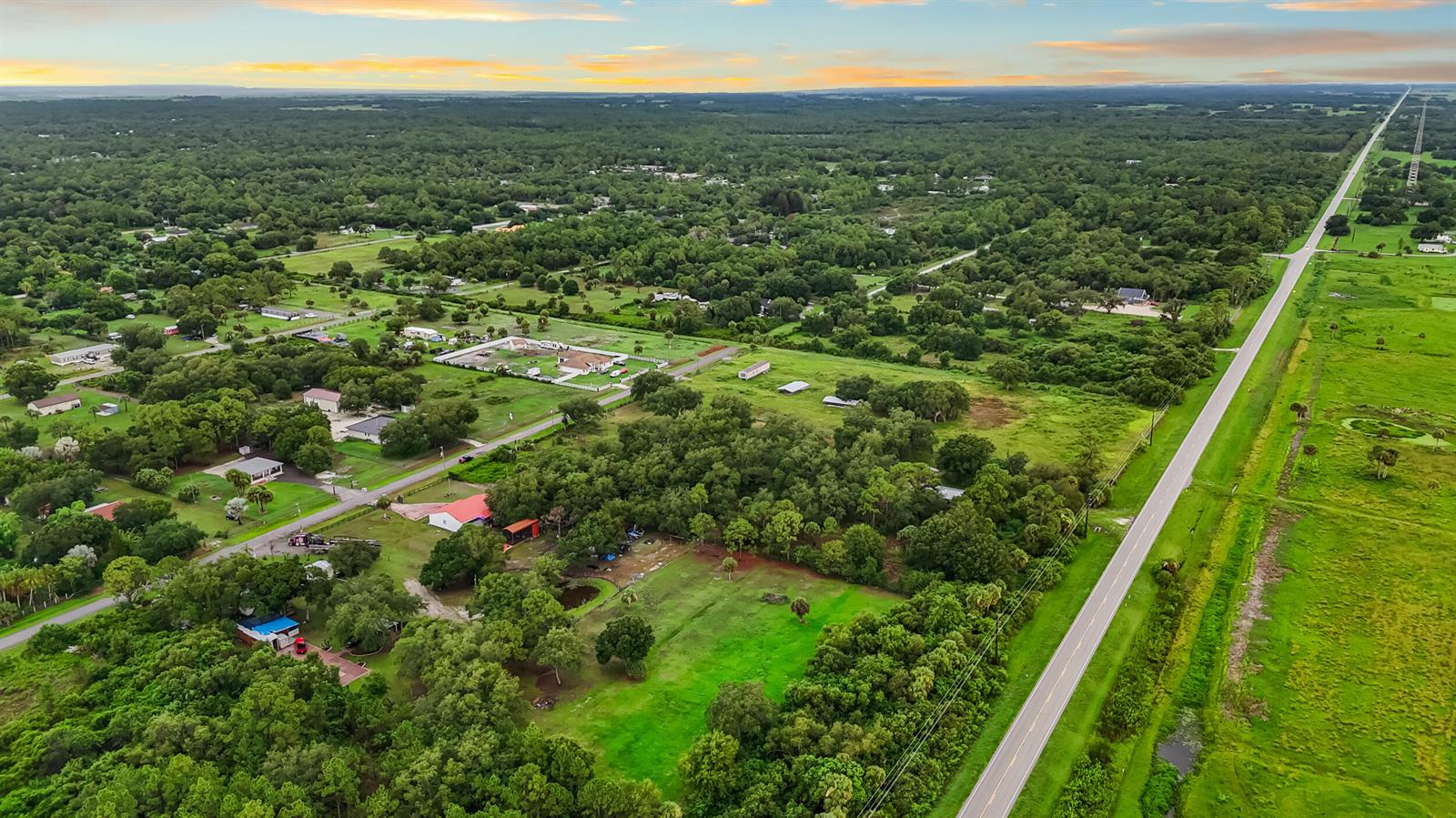 An aerial view shows a rural landscape with scattered houses, dense trees, and a straight road — 340 S Arboleda Street, Clewiston FL 33440, CLEWISTON, FL