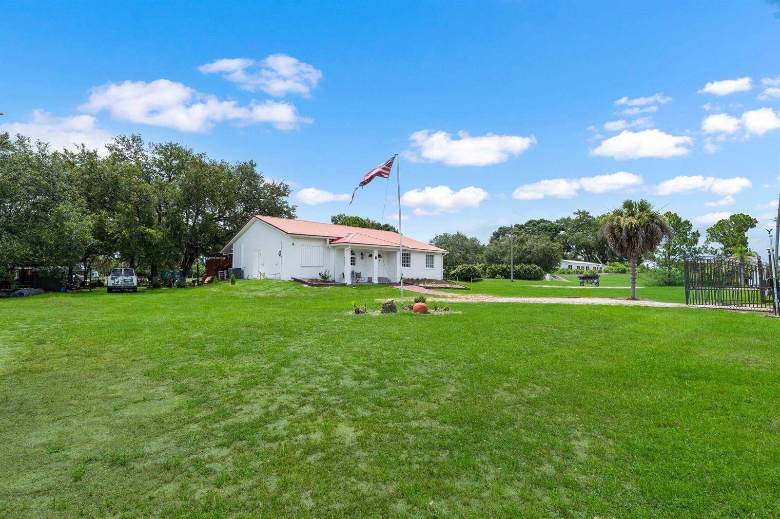 A white house with a red metal roof sits on a large, grassy lot — 340 S Arboleda Street, Clewiston FL 33440, CLEWISTON, FL