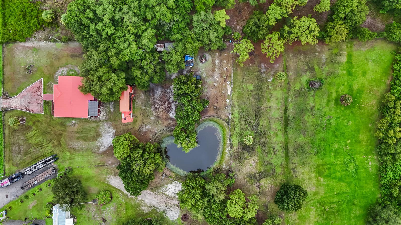 An aerial view shows a rural property with a red-roofed house, pond, and grassy fields — 340 S Arboleda Street, Clewiston FL 33440, CLEWISTON, FL