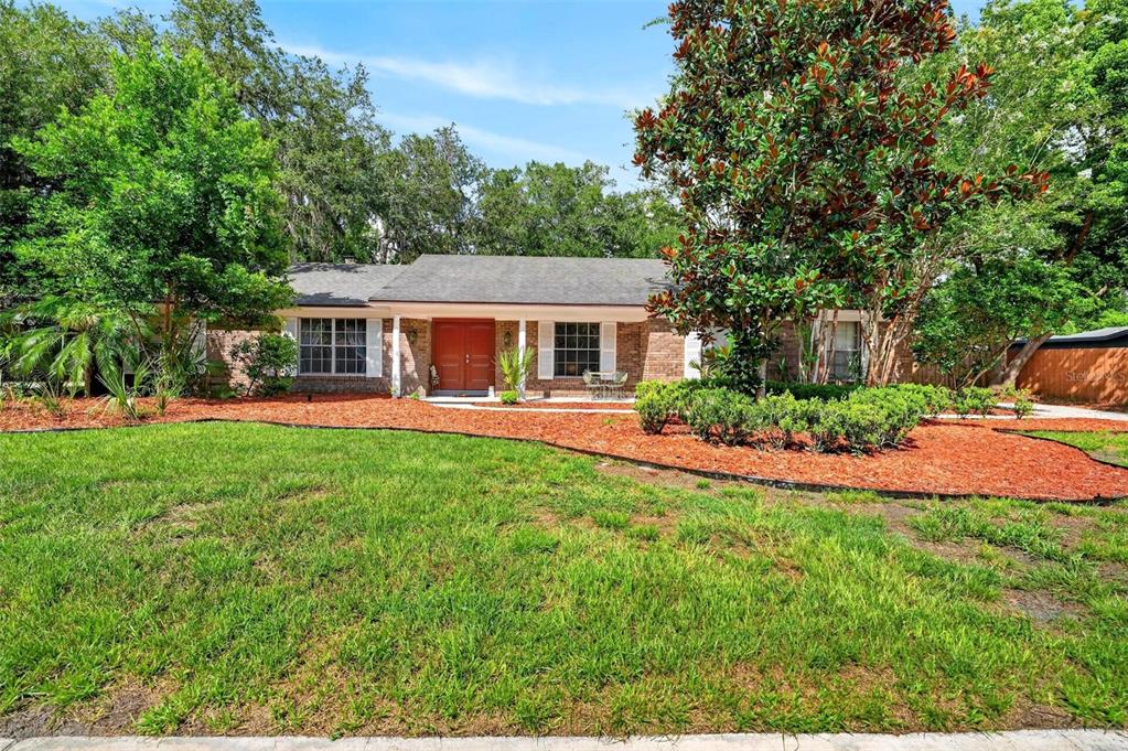 A single-story brick house with a red double front door and a large front lawn — 209 ROYAL OAKS CIRCLE, LONGWOOD, FL