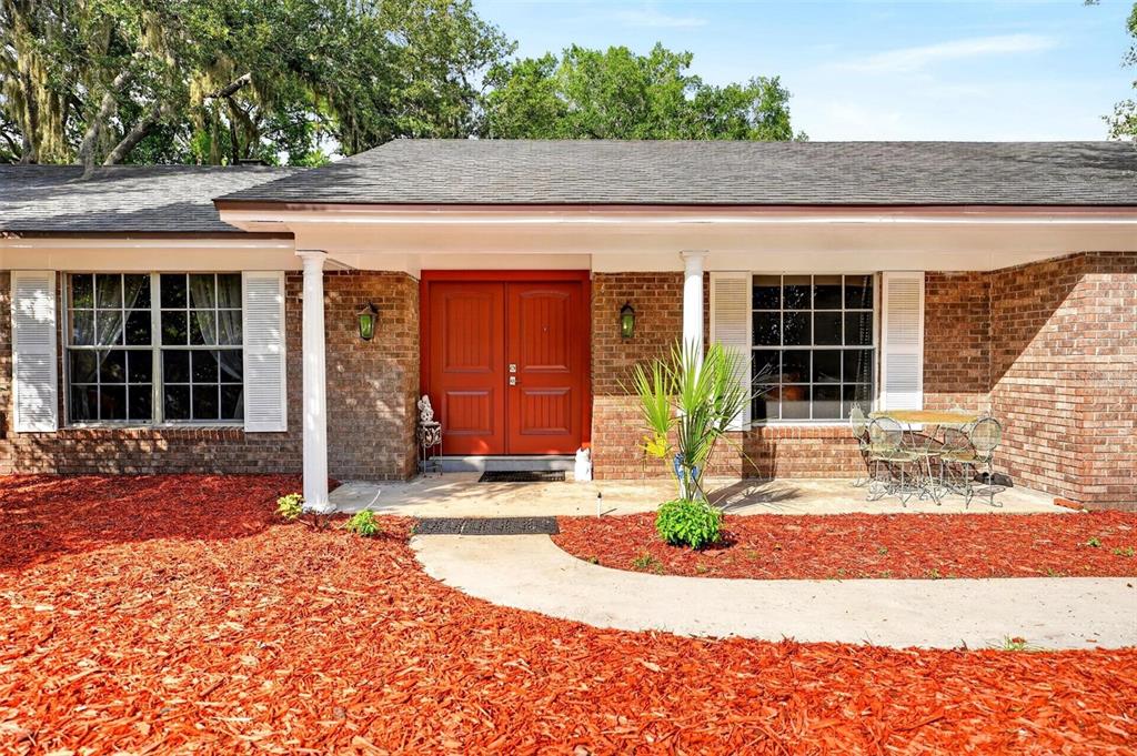 A brick house exterior features a red double front door and a concrete walkway — 209 ROYAL OAKS CIRCLE, LONGWOOD, FL