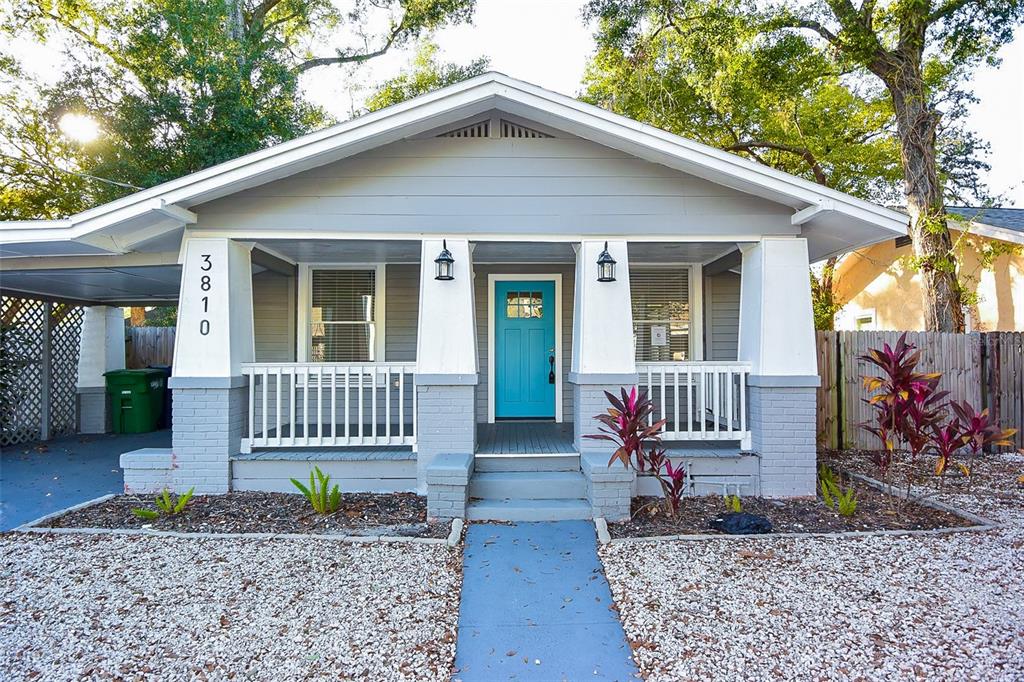 A single-story house with a blue front door, a covered porch, and a gravel yard — 3810 N ARLINGTON AVENUE, TAMPA, FL