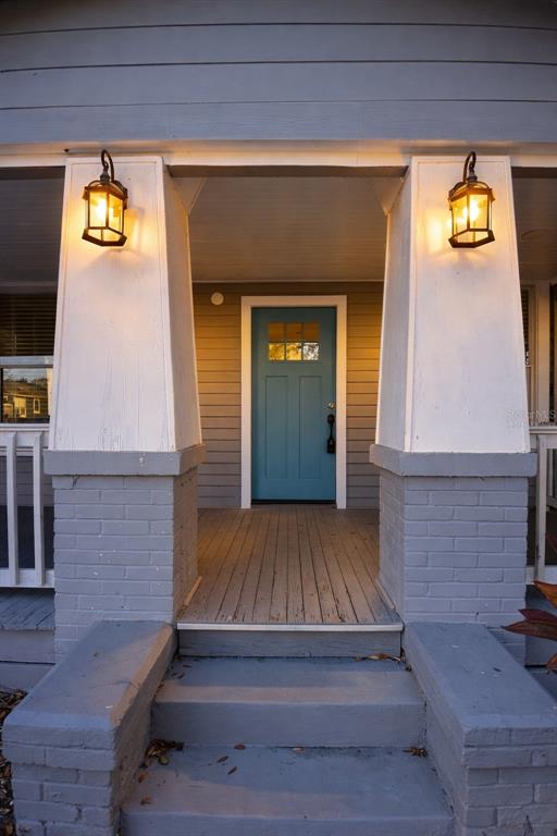 A front porch features a teal door, two lit lanterns, and gray brick columns — 3810 N ARLINGTON AVENUE, TAMPA, FL