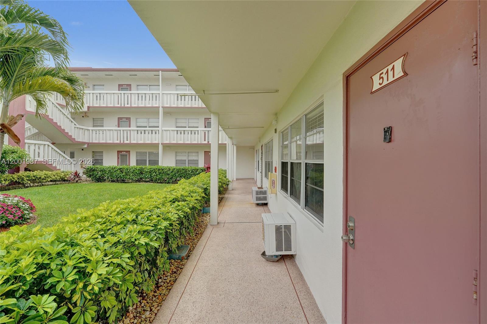 An exterior walkway leads past a unit door numbered 511 toward a multi-story apartment building — 511 Fanshaw M # 511, Boca Raton FL 33434, BOCA RATON, FL
