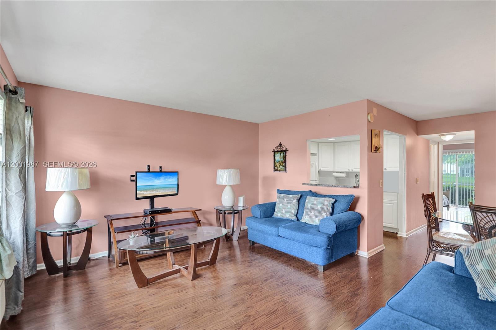 A living room features pink walls, dark wood flooring, and blue furniture — 511 Fanshaw M # 511, Boca Raton FL 33434, BOCA RATON, FL