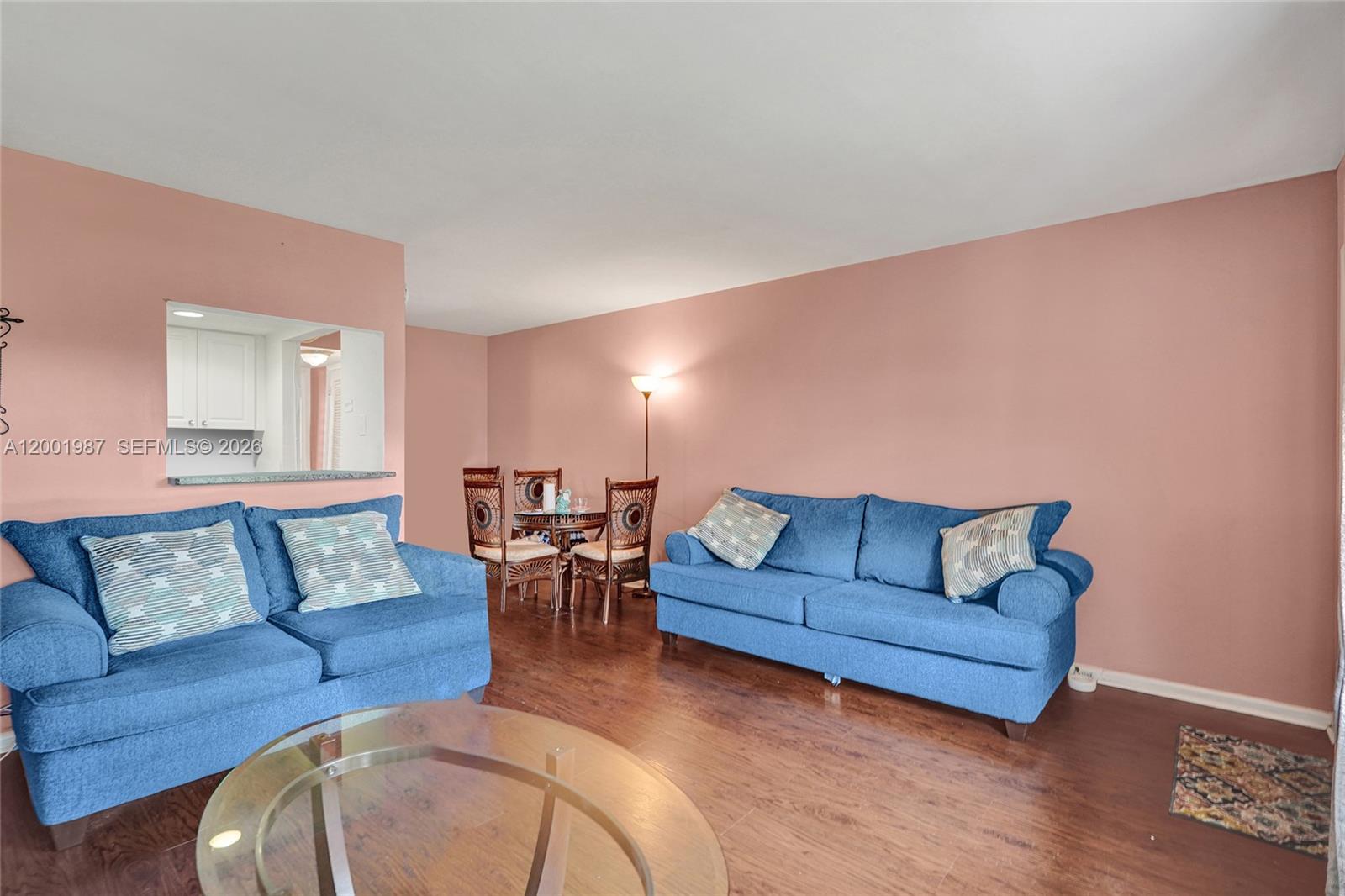 A living room features pink walls, wood-look flooring, and two blue sofas — 511 Fanshaw M # 511, Boca Raton FL 33434, BOCA RATON, FL