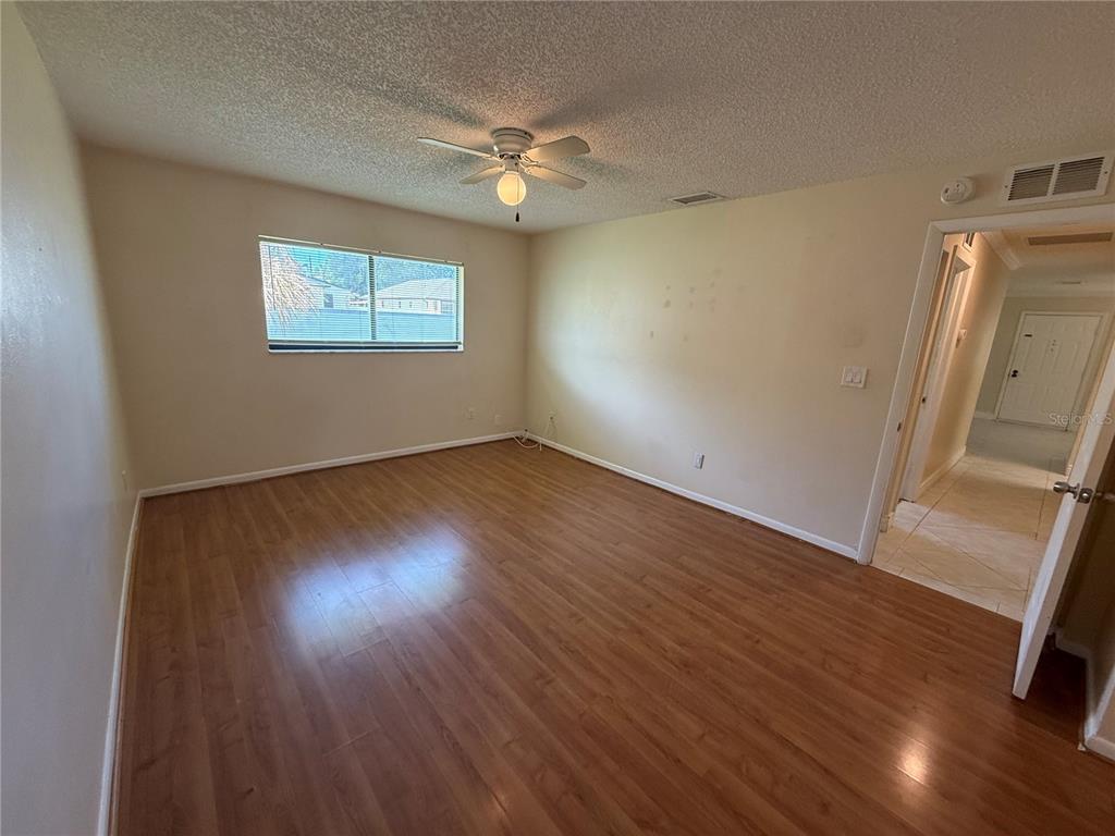 An empty bedroom features wood-look laminate flooring, a ceiling fan, and a window — 5130 70TH PLACE N, PINELLAS PARK, FL