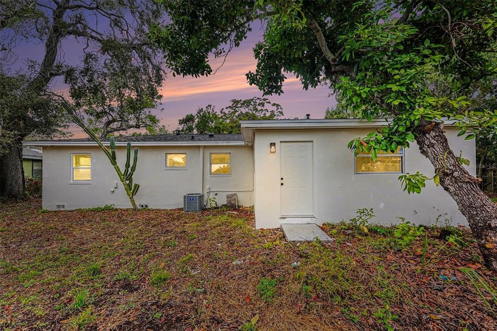 The exterior of a single-story house features a white wall, a door, and several windows — 2560 QUEENSBORO AVENUE S, ST PETERSBURG, FL