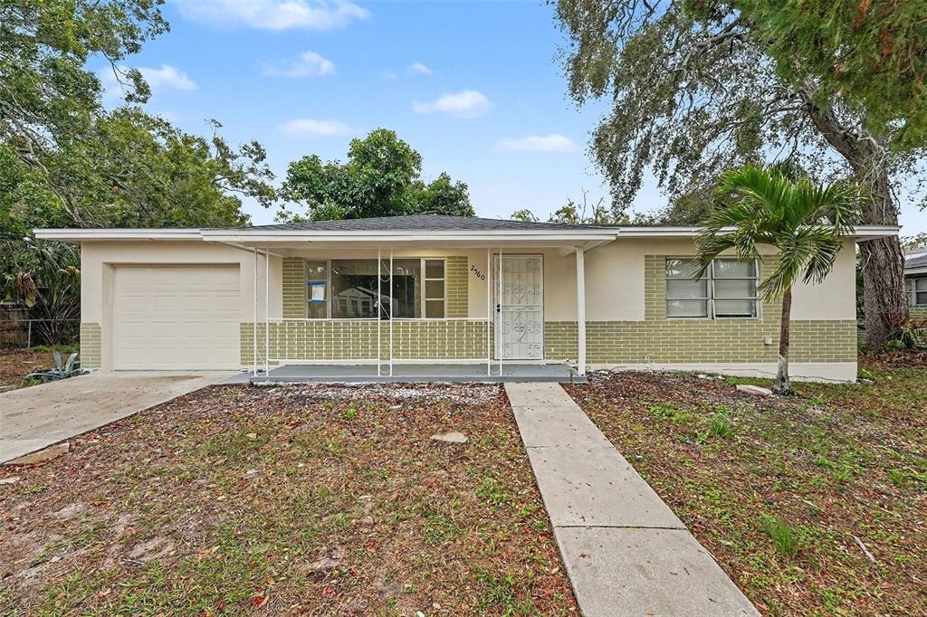 A single-story house with a beige exterior, brick accents, a garage, and a front porch — 2560 QUEENSBORO AVENUE S, ST PETERSBURG, FL