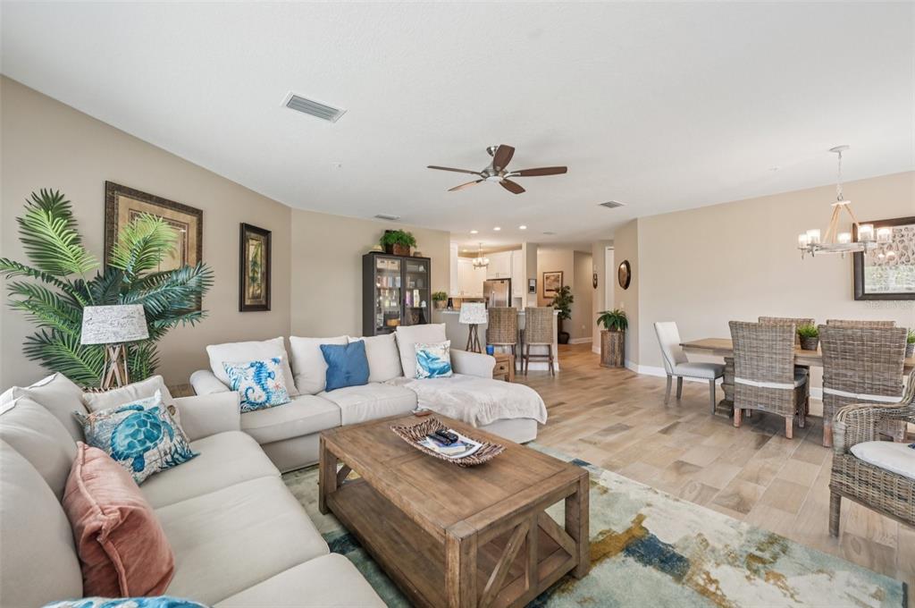 A living room and dining area feature light wood floors, neutral walls, and coastal decor — 3440 77TH STREET W UNIT 201, BRADENTON, FL