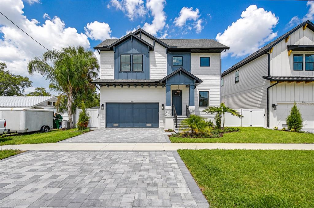 A two-story house with white siding, blue accents, a paved driveway, and a front porch — 7303 S FITZGERALD STREET, TAMPA, FL