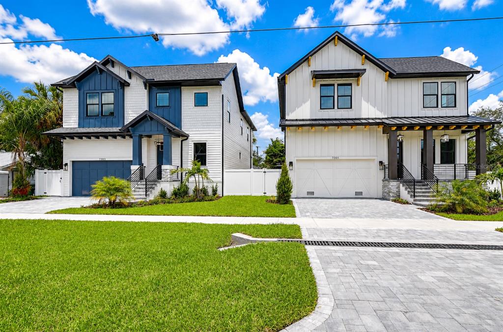Two modern two-story houses with white siding and attached garages stand side-by-side on a lawn — 7303 S FITZGERALD STREET, TAMPA, FL