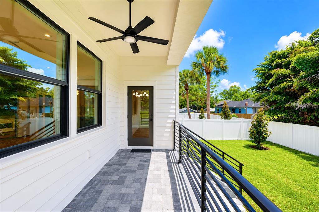 A covered patio with a ceiling fan, black railings, and a view of the backyard — 7303 S FITZGERALD STREET, TAMPA, FL