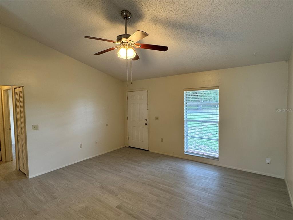 An empty room features light-colored wood-look flooring, a ceiling fan, and a single window — 10041 MASSEY STREET, ORLANDO, FL