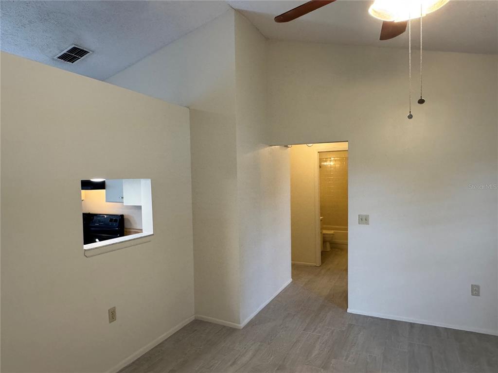 A view of a room with light-colored tile flooring, a pass-through window, and a bathroom — 10041 MASSEY STREET, ORLANDO, FL
