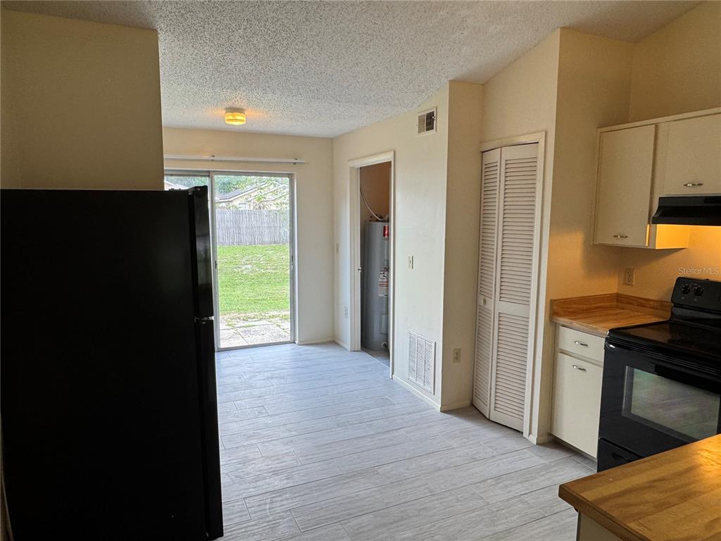 A kitchen with light-colored cabinets, wood countertops, black appliances, and a sliding glass door — 10041 MASSEY STREET, ORLANDO, FL