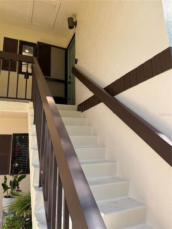 An outdoor staircase with brown railings leads to a landing with a front door — 19505 QUESADA AVENUE UNIT U204, PORT CHARLOTTE, FL